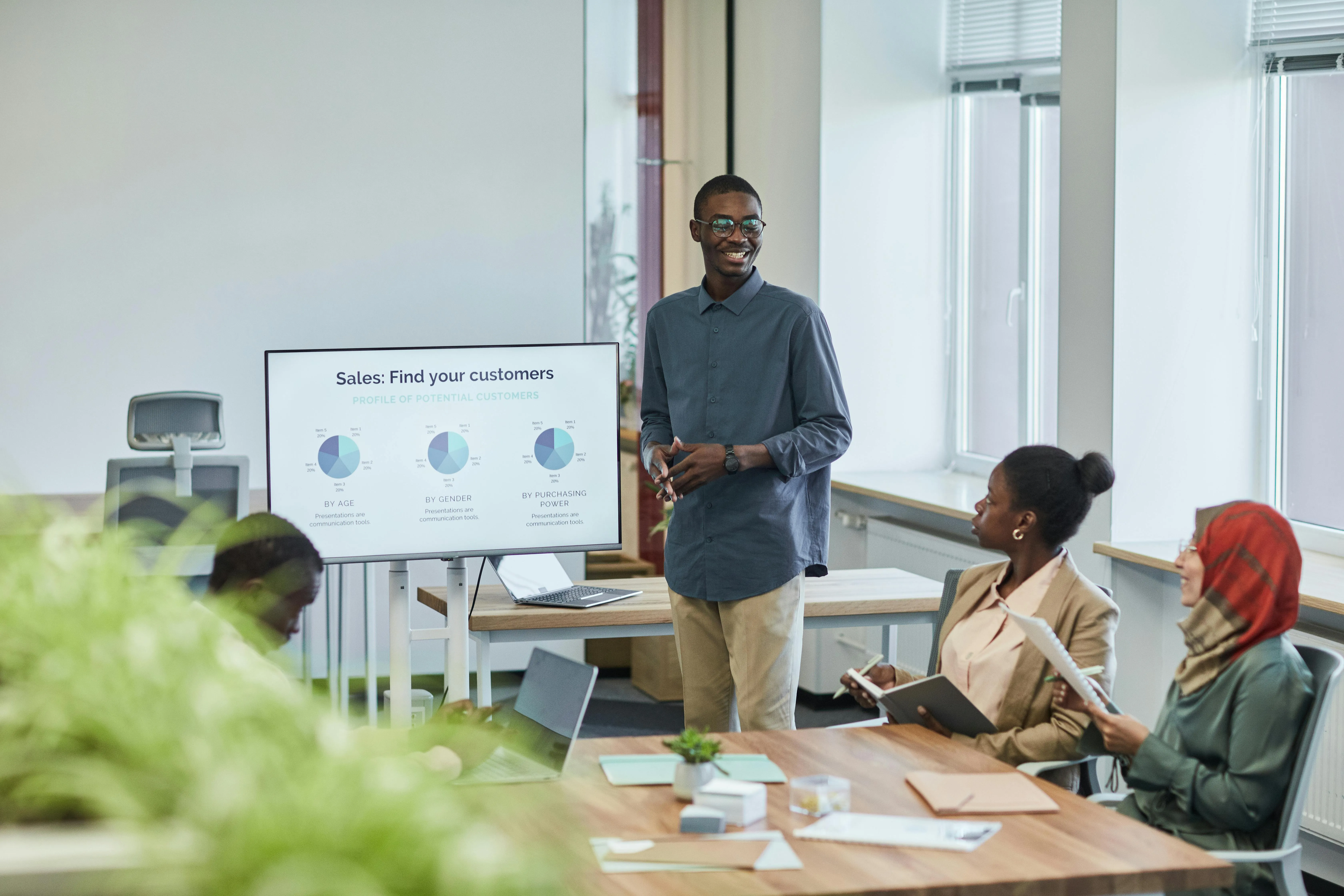 A meeting between marketers with donut charts of sales behind them