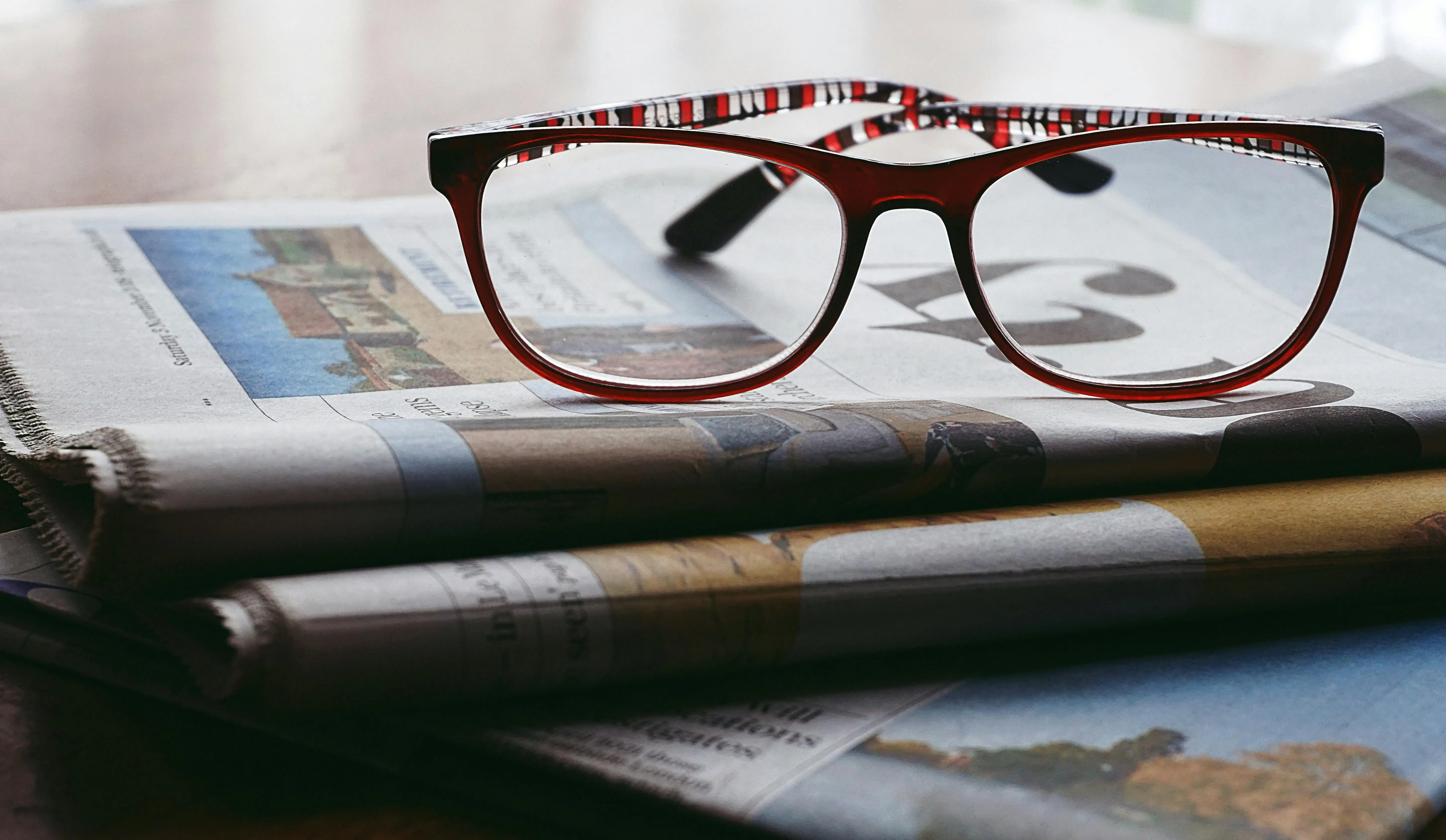 A pair of spectacles resting on top of newspapers